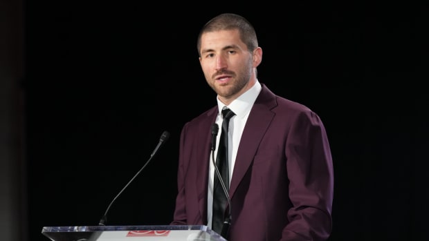JC Tretter talks into a microphone standing at a podium
